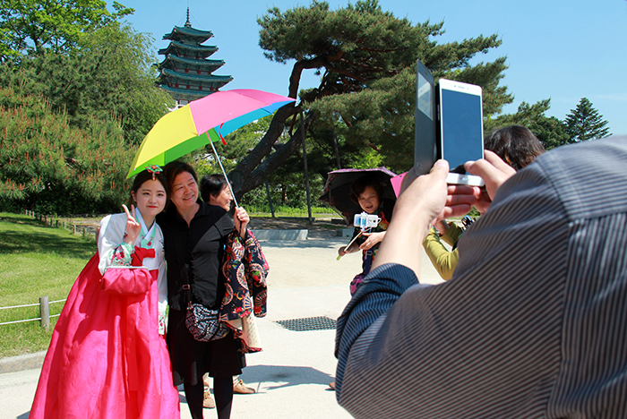 穿韩服的游客们笑着应对外国游客接二连三的合影要求。