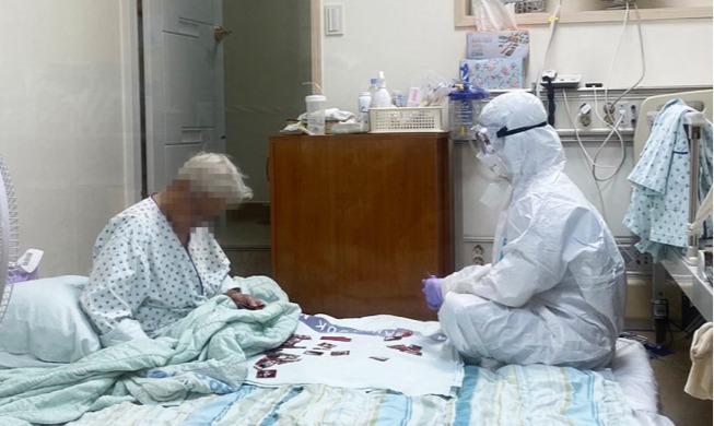 让国民感动的《穿防护服的护士和奶奶玩花纸牌》的照片