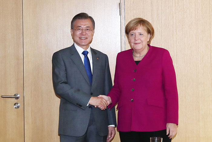 当地时间10月19日，韩国总统文在寅（左）出席在比利时布鲁塞尔举行的第12届亚欧首脑会议，与德国总理安格拉·默克尔握手。