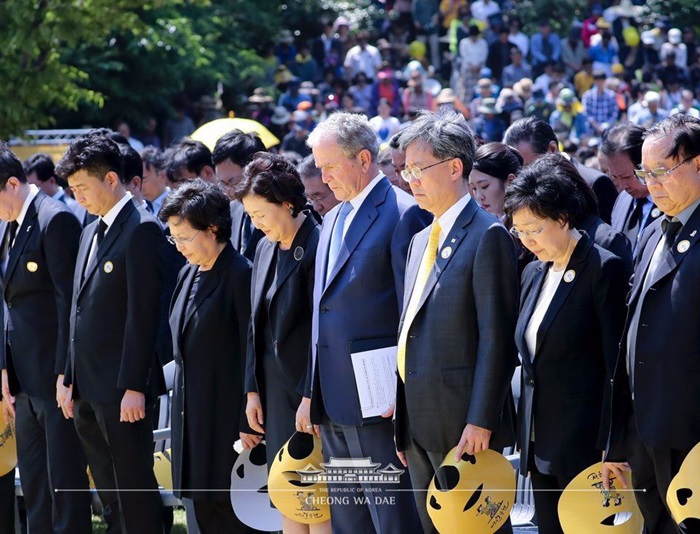 5月23日下午2时，在庆尚南道金海市峰下村举行的韩国前总统卢武铉逝世十周年纪念活动上，出席者们正在哀悼。从左二起依次为卢武铉之子卢建昊、卢武铉妻子权良淑、韩国总统文在寅夫人金正淑、美国前总统乔治•布什。图片来源：青瓦台