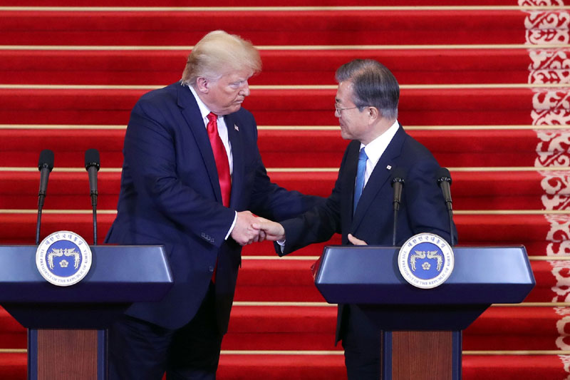 6月30日，韩国总统文在寅（右）与美国总统特朗普在首脑会晤后举行的共同记者会上握手。文在寅表示，朝美首脑今天将首次在象征韩朝分裂的板门店为和平握手。图片来源：韩联社