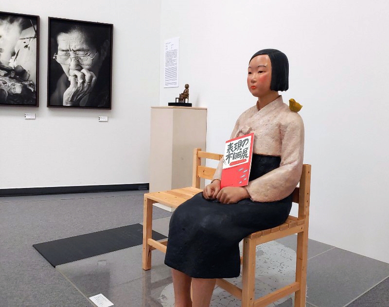 일본 아이치현 나고야시에서 열리고 있는 일본 국제예술제 ‘아이치 트리엔날레 2019’에 출품된 ‘평화의 소녀상’에 '표현의 부자유전’ 팸플릿이 들려있다. 연합뉴스