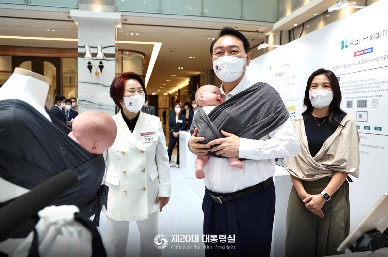 7月5日，在首尔市汝矣岛中小企业中央会馆举行的第一届女性企业开幕式上，韩国总统尹锡悦访问了育儿用品企业Konny by Erin展位，并亲自试戴婴儿背带。图片来源：韩国第20届总统室