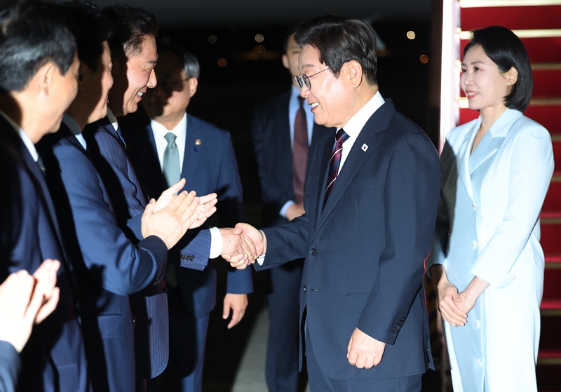 6月19日，韩国总统李在明结束七国集团（G7）峰会后返回，在抵达城南首尔机场时，与前来迎接的共同民主党院内代表金炳基等人握手致意。图片来源：韩联社
