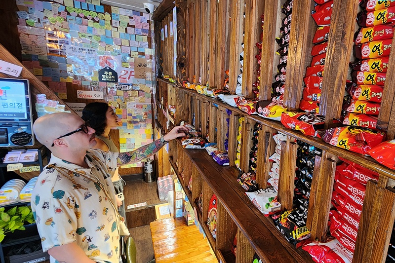 图为2024年8月6日，在首尔一家便利店，外国人正在挑选拉面。图片来源：韩联社