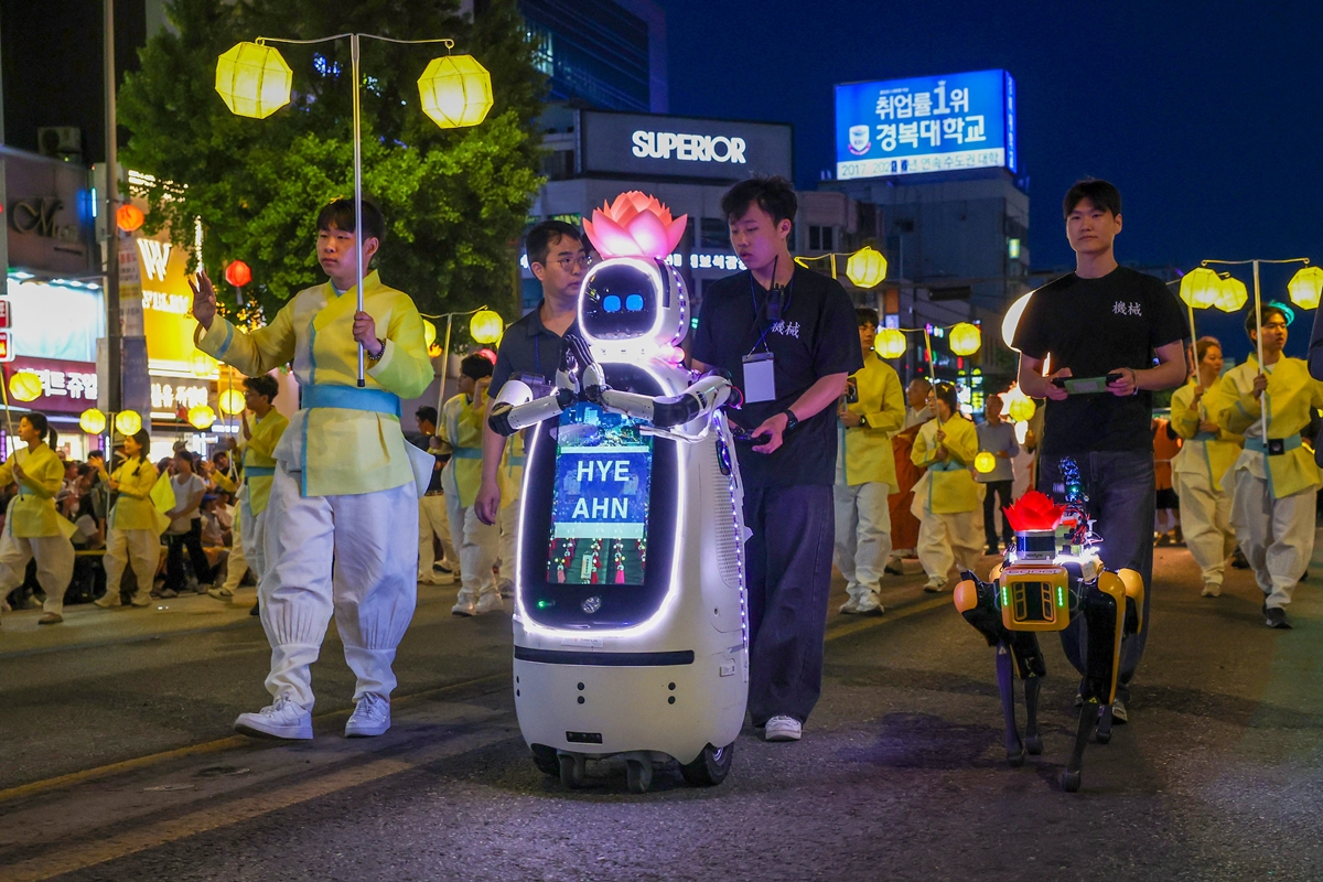 图为5月16日，在韩国佛诞节前夕，首尔钟路一带举行的燃灯游行活动上，东国大学方队中的AI机器人僧侣“慧安”（左）与巡逻安全多传感四足机器人Googi。韩宣网记者李廷佑 摄