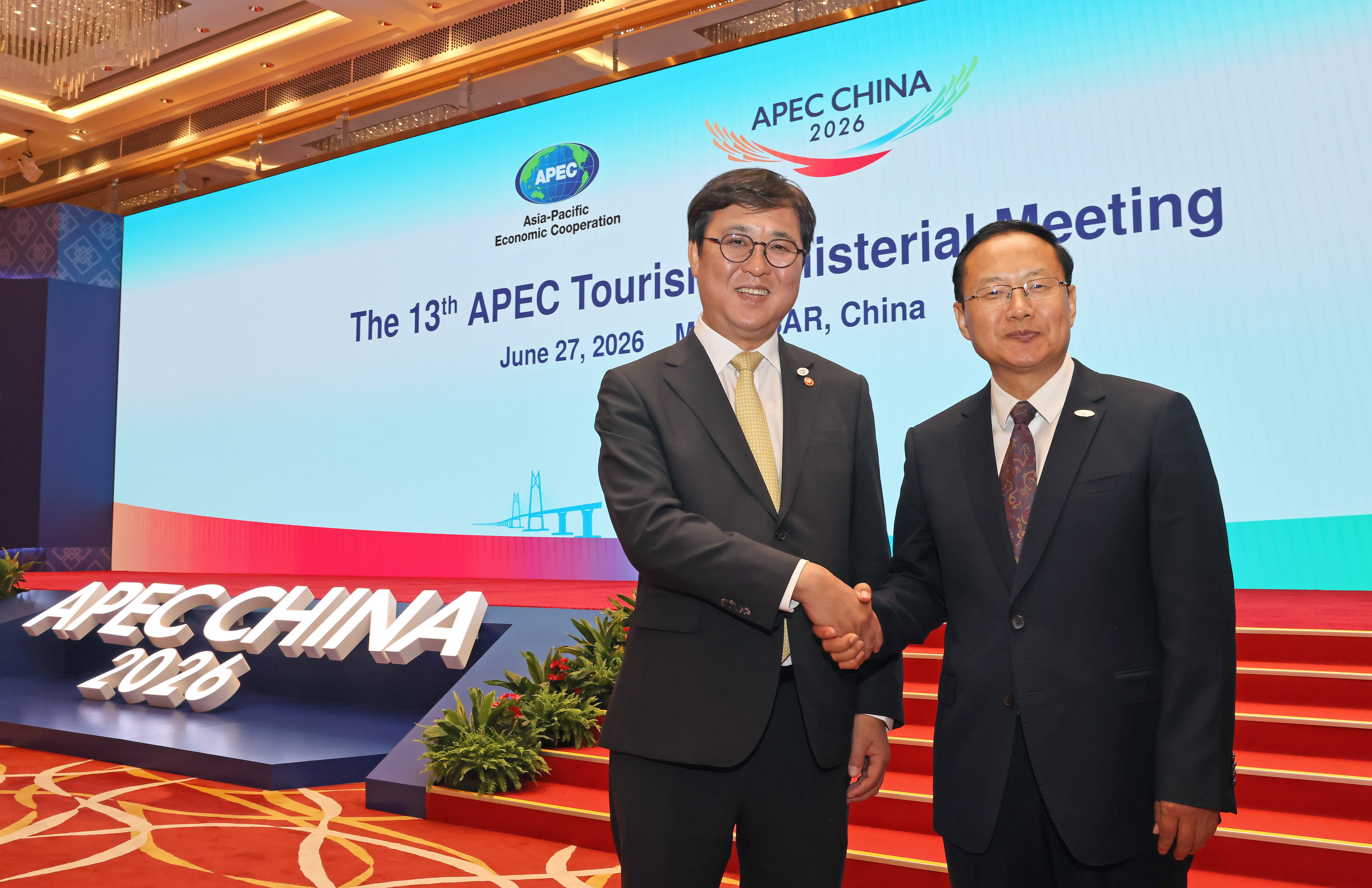 6月27日，韩国文化体育观光部长官崔辉永（左）在中国澳门举行的第13届亚太经合组织（APEC）旅游部长会议全体会议结束后，与中国文化和旅游部部长孙业礼握手并合影留念。韩国文化体育观光部许满镇 摄