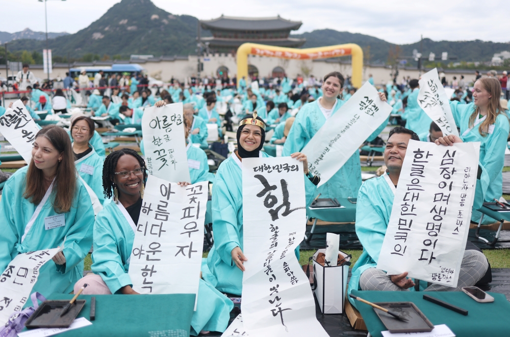 7月18日至19日，国立中央科学馆将举办“K-Pop热潮背后的秘密：充满节奏感的韩文”体验活动。图片为去年9月在首尔光化门广场举行的“纪念韩文创制579周年书法大会”上，外国人参与者展示自己书写的韩文作品。图片来源：韩联社