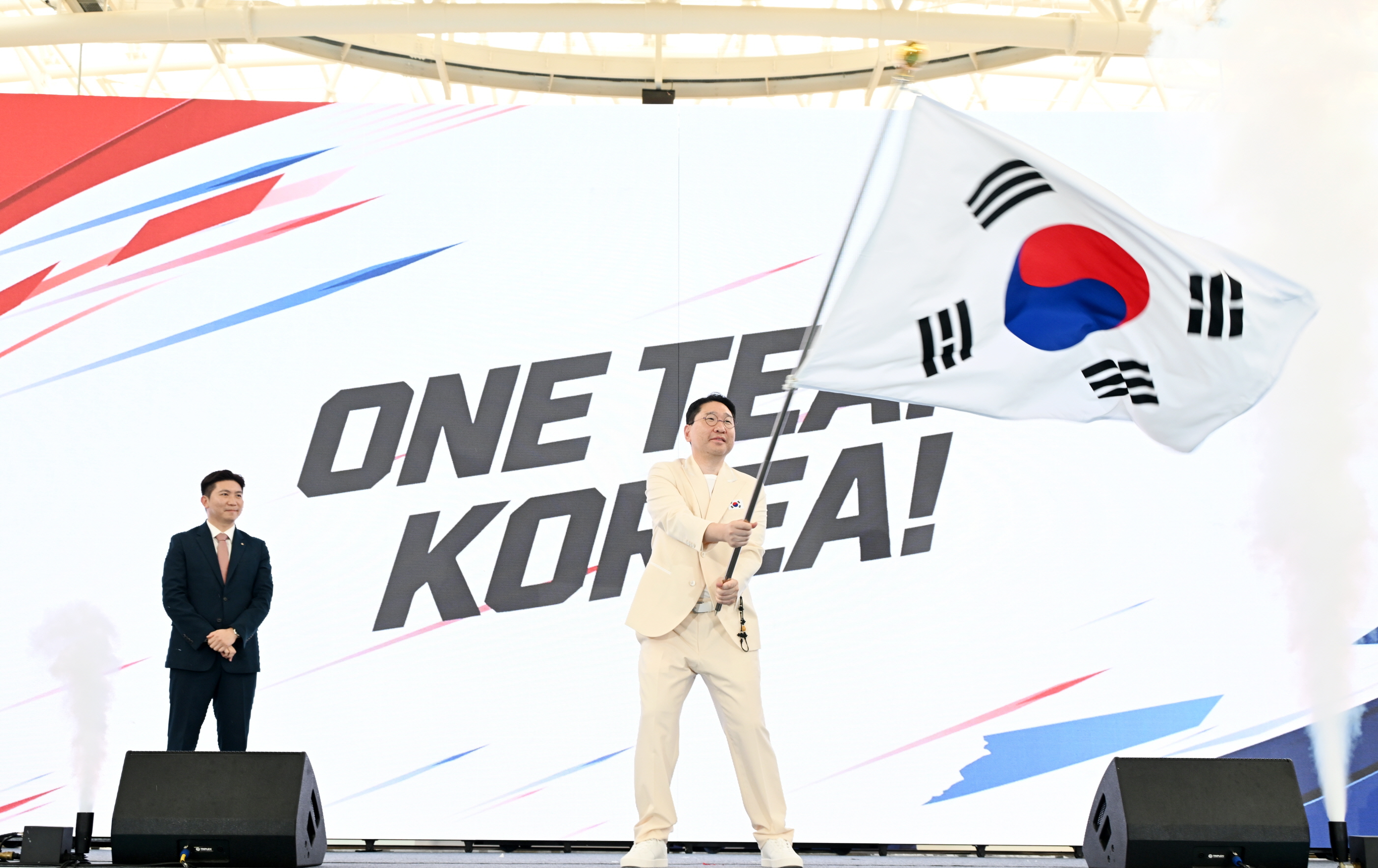9月3日，在忠清北道镇川国家运动员村举行的2026年爱知&middot;名古屋亚运会韩国体育代表团出征仪式上，韩国体育代表团团长李祥铉挥舞国旗。图片来源：大韩体育协会