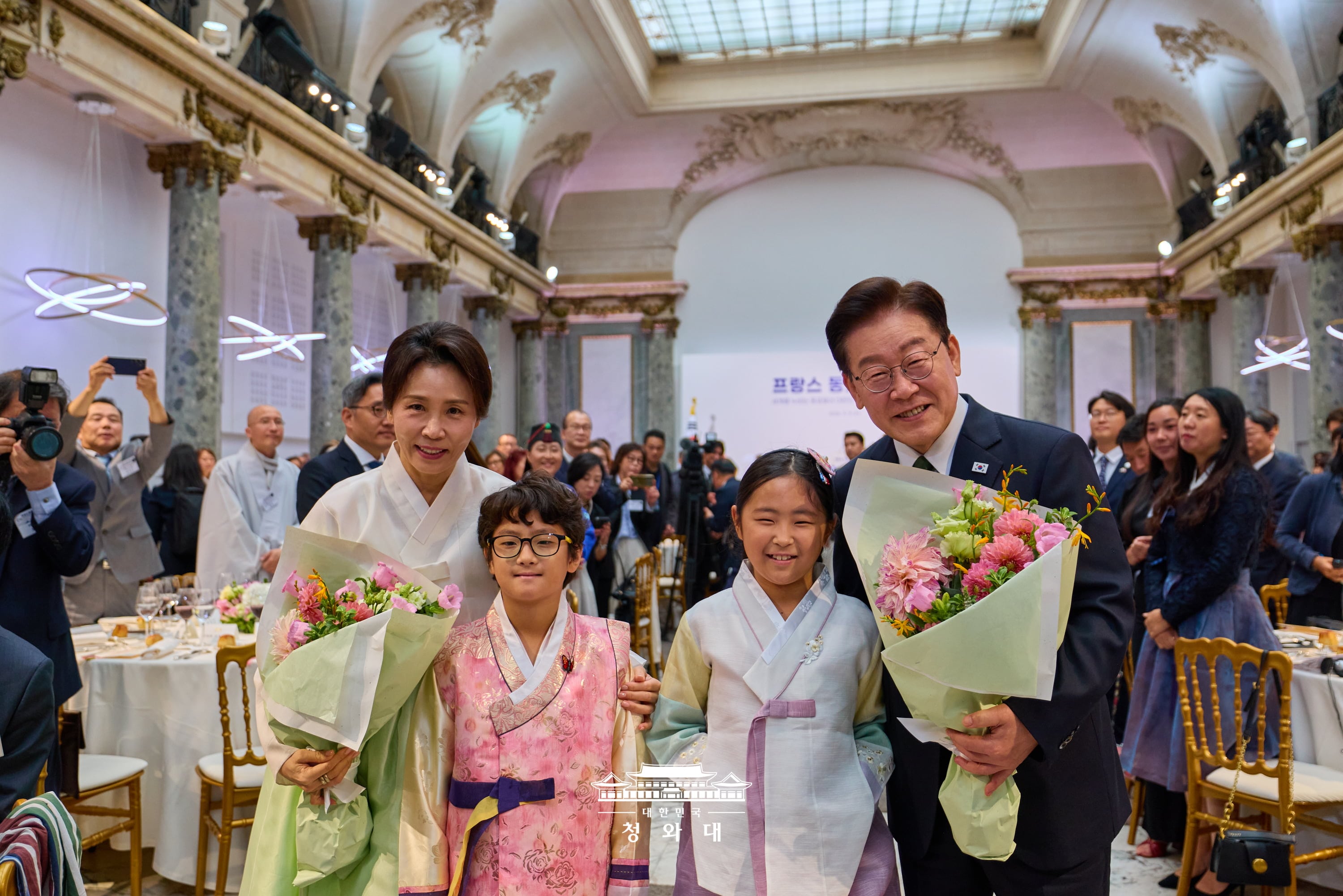 当地时间9月9日，韩国总统李在明与夫人金惠景在法国巴黎举行的旅法韩侨午餐座谈会上，与献花的孩子们合影。图片来源：大韩民国青瓦台