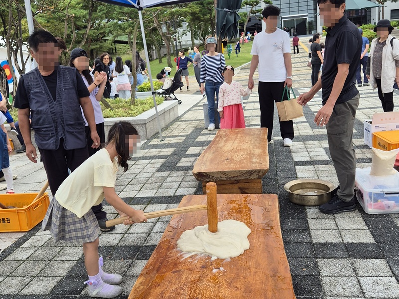图为2025年10月3日至7日，在全罗北道全州市完山区国立全州博物馆举行的&ldquo;中秋民俗游戏广场&rdquo;活动中，游客体验捶打年糕。图片来源：国立全州博物馆
