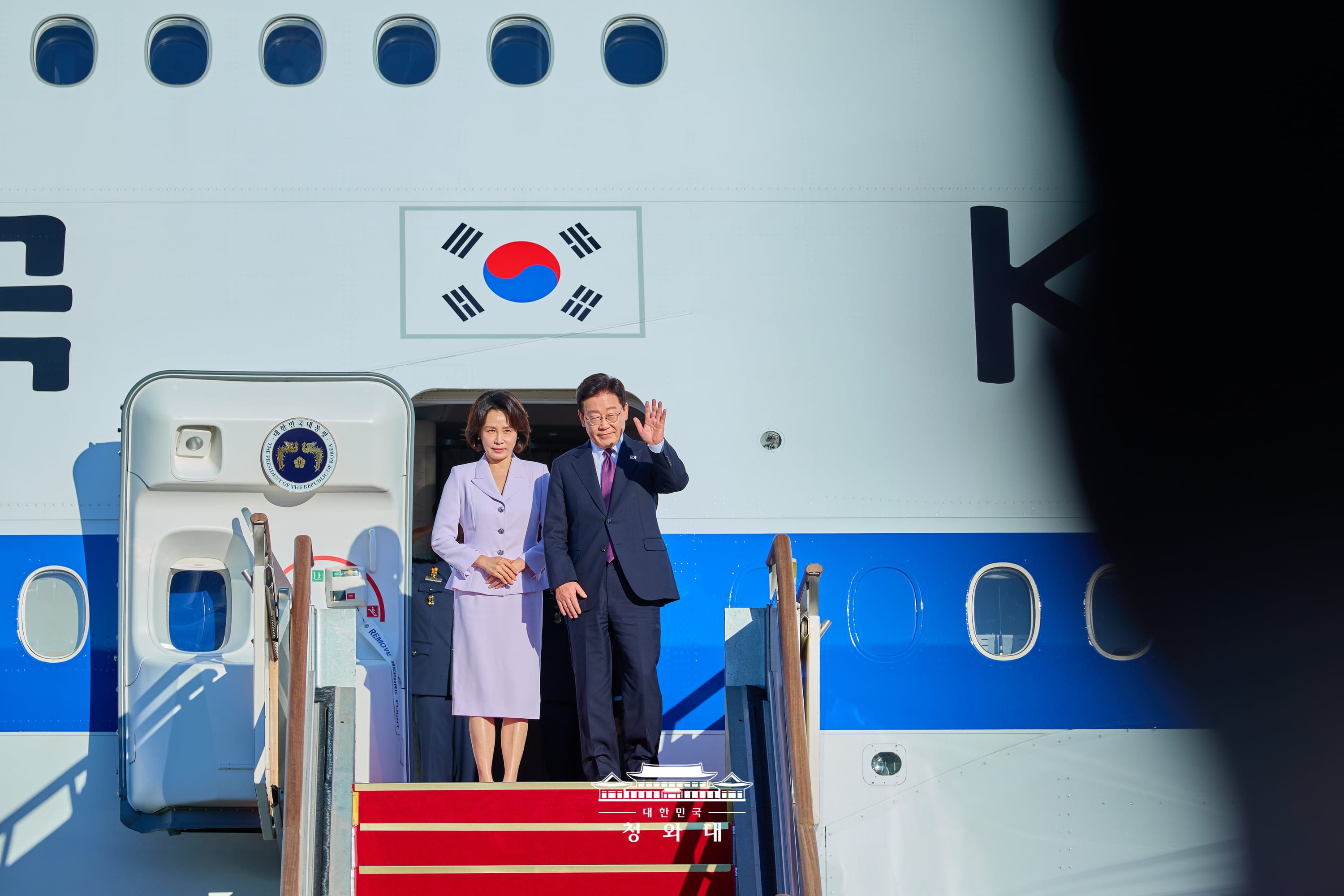 9月21日，在京畿道城南市首尔机场，韩国总统李在明（右）与夫人金惠景登上&ldquo;空军一号&rdquo;总统专机，并向前来送行的人士挥手致意。图片来源：大韩民国青瓦台
