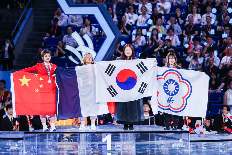 9月27日，在中国上海国家会展中心举行的第48届世界技能大赛闭幕式上，获得美发项目金牌的韩国选手金祚英（音）手持太极旗庆祝。图片来源：世界技能大赛