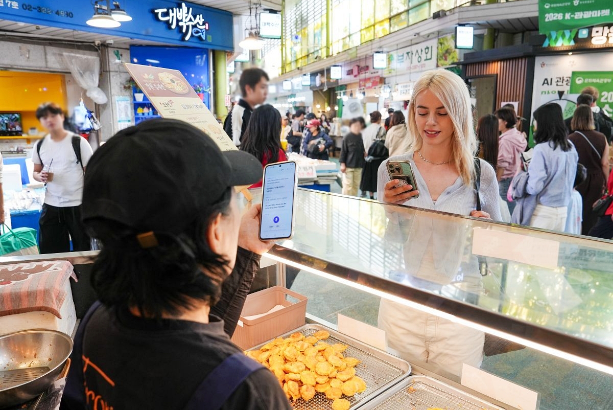 10月22日，韩国文化体育观光部发布《2026年9月访韩旅游趋势》报告。数据显示，今年1月至9月，访韩外国游客累计达1711万人次。图为外国游客在传统市场，利用“AI旅游管家”的多语言翻译功能与商贩交流。图片来源：韩国旅游发展局