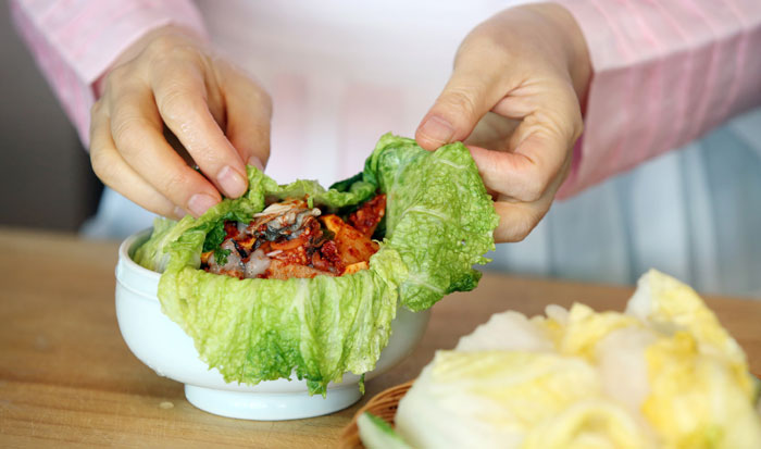 김치보시기에 배춧잎을 3~4장정도 펴놓고, 버무린 김치를 먹음직스럽게 담은 후, 남은 해물과 고명을 얹어, 밑에 깔아놓은 배춧잎으로 덮어서 꼭 오므린다.