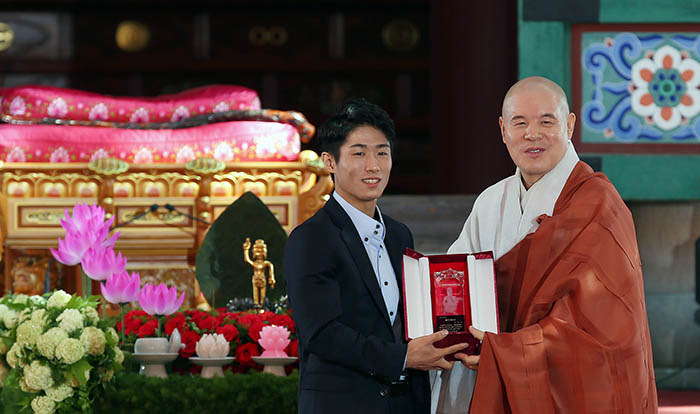 在佛诞节“奉祝法会主要仪式”上，曹溪宗总务院长慈乘大师（右）向2013年起担任曹溪宗中央信徒会希望幸福会形象大使的体操选手梁鹤善授予佛家弟子大奖。
