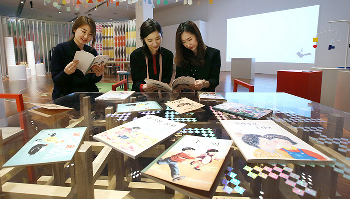 국립한글박물관 특별전 ‘슬기롭게 사이좋게’는 광복 이전부터 현재까지 초등학교 교과서를 통해 공동체의 꿈을 소개한다. 관람객들이 전시장에 마련된 책상에서 옛날 교과서를 읽고 있다.