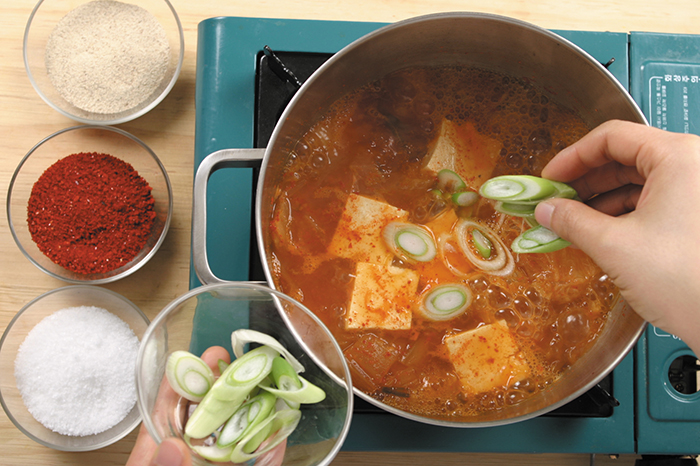 볶은 돼지고기와 배추김치에 찌개 국물과 고춧가루를 넣고, 30분 정도 더 끓인다. 기호에 따라 고춧가루를 더 넣거나 김치 국물을 더 넣을 수도 있다.