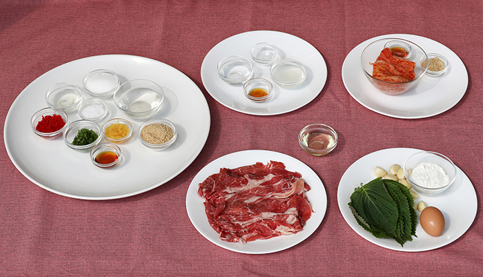 단군신화전의 재료인 얇게 썰은 쇠고기 등심, 마늘, 배추김치, 깻잎, 밀가루, 각종 양념.