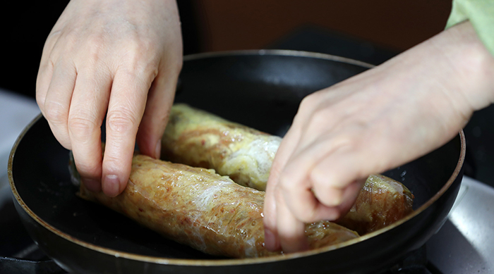 말아낸 마늘과 김치와 쇠고기에 달걀물을 입힌 뒤 달궈진 프라이팬에 기름을 두르고 지진다.