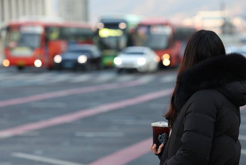 图为在首尔钟路区，早晨最低气温达零下11度的一天，一位市民手拿冰美式咖啡。图片来源：韩联社