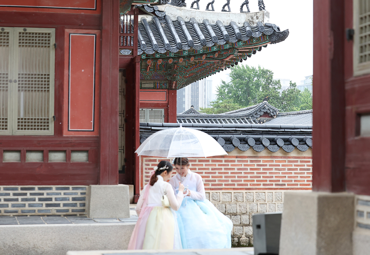 6月20日，在首尔钟路区景福宫，两位外国游客撑着雨伞在雨中漫步。根据天气预报，从今天开始韩国将进入梅雨季节，全国大部分地区有降雨。