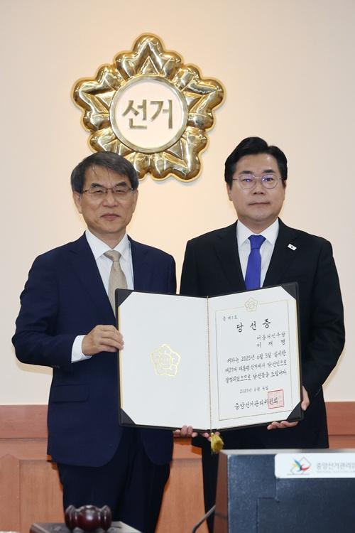6月4日，在位于京畿道果川市的中央选举管理委员会，选管会委员长卢泰岳（左）向共同民主党代理党首朴赞大转达了李在明的总统当选证书。图片来源：韩联社
