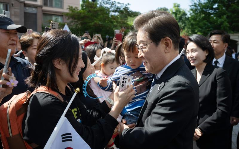 6月4日，在仁川市桂阳区，韩国新任总统李在明准备出发前往国立显忠院前，与等候在私宅前的居民握手致意。当天，李在明私宅前处处悬挂着祝贺当选总统的条幅。图片来源：政府共同采访团