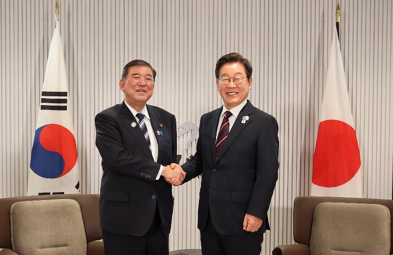 当地时间6月17日，韩国总统李在明在加拿大艾伯塔省卡纳纳斯基斯举行的七国集团（G7）峰会场馆内，与日本首相石破茂握手并合影留念。图片来源：韩联社