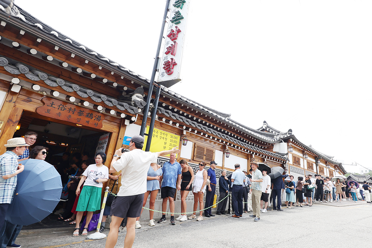 7月30日为二十四节气中的中伏。图为在首尔市钟路区的一家参鸡汤店门口，人们正排队等候。中伏是夏季最热的时段，在韩国有喝参鸡汤补身体的习俗。