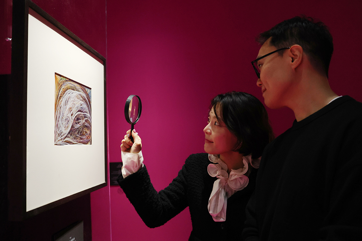 11月12日，在首尔市中区首尔市立美术馆举行的首尔媒体城市双年展《降灵：灵魂的技术》展览中，来访者正手持放大镜欣赏作品。