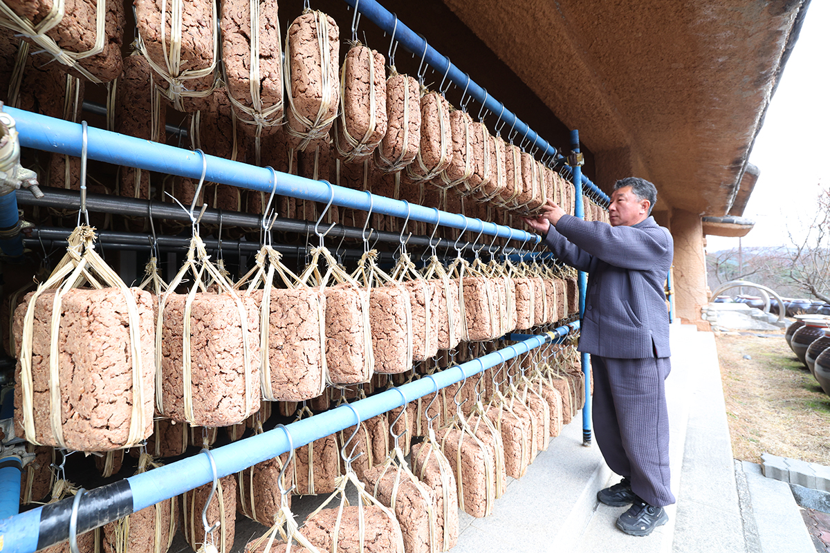 12月17日，在江原道江陵市城山面大关岭脚下的一家传统制酱工坊里，用传统方式制成的一串串豆酱坯在风和阳光下慢慢发酵。