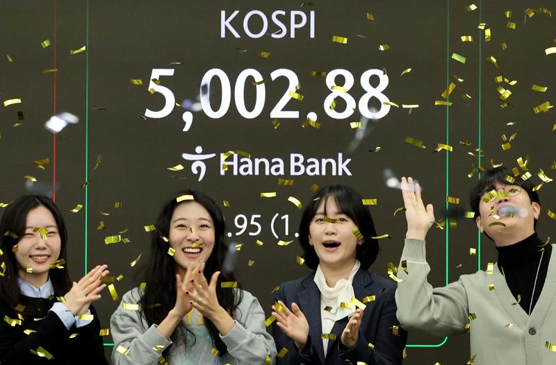 韩国综合股价指数（KOSPI）史上首次突破5000点。1月22日上午，在首尔中区韩亚银行交易室内，交易员们欢呼庆祝。图片来源：韩联社