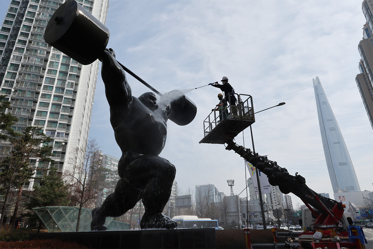 3月25日，在首尔松坡区蚕室洞，工作人员正在清洗一座奥林匹克雕塑。