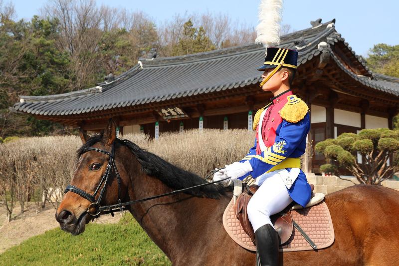 张元赫士官生（三年级）骑行经过朝鲜王朝最高军事机构“三军府”清宪堂前。军马队证明，力量并不只意味着强大与迅捷，井然有序本身也是一种强大力量。