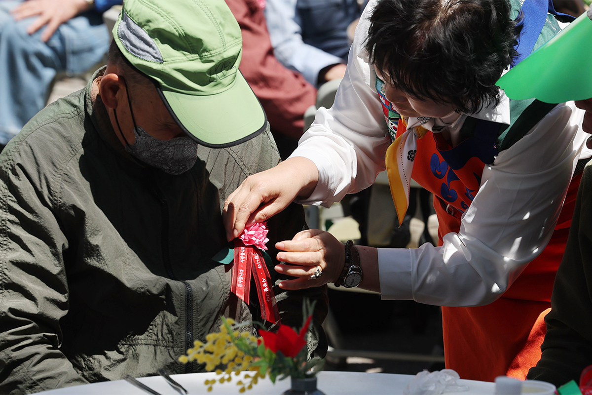 5月8日，在首尔东大门区举行的父母节纪念活动中，志愿者们正在为老人佩戴康乃馨。