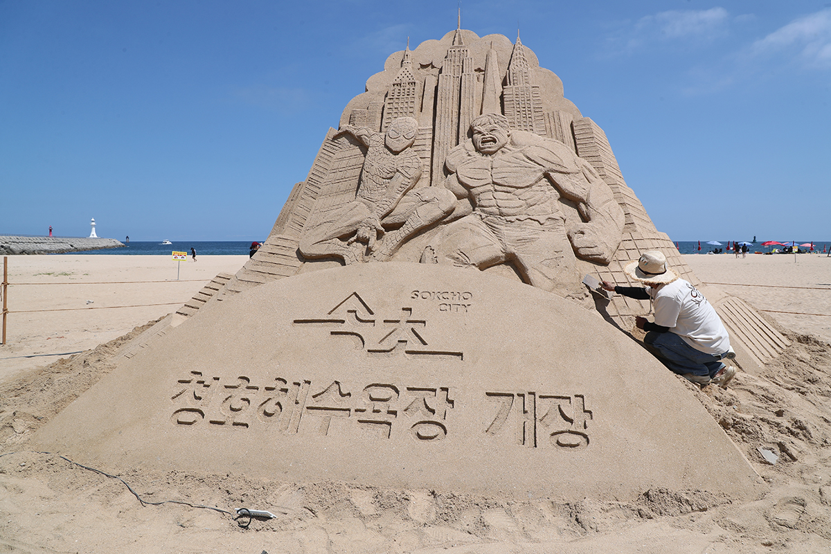 8月5日，在江原道束草市青湖海水浴场沙滩上，工作人员正在制作蜘蛛侠和绿巨人沙雕作品。