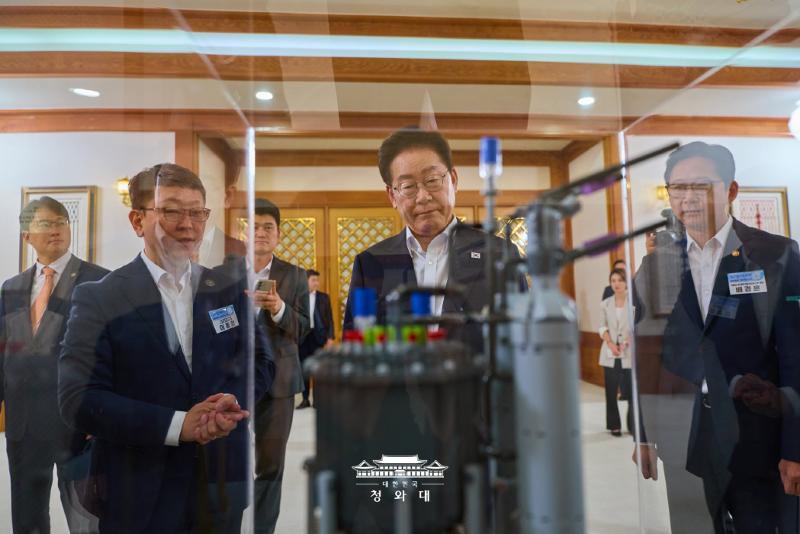 6月12日，韩国总统李在明（前排左二）在青瓦台举行的“未来增长动力七大种子计划”报告会开始前，视察搭载SMR的集装箱船模型。图片来源：大韩民国青瓦台